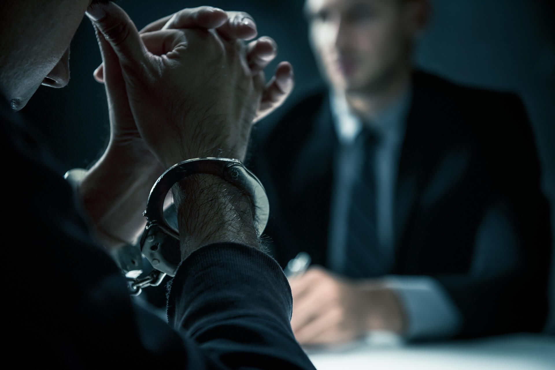 Man wearing handcuffs talking to a lawyer